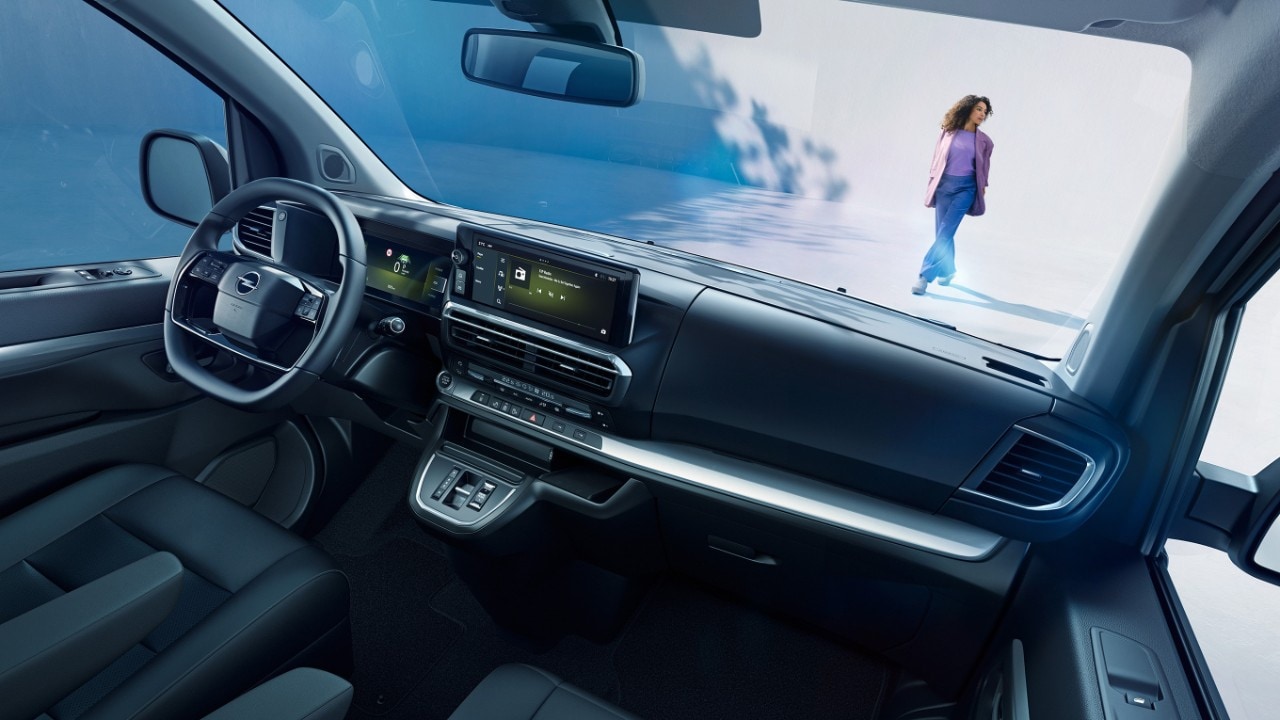 Pohľad do interiéru bieleho modelu Opel Zafira zo sedadla spolujazdca so ženou vonku